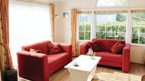 A room with two red sofas, a white coffee table, and large windows with curtains. - 2 bedroom nice home in Tzummarum (Tzummarum)