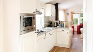A compact kitchen with white cabinetry, a built-in oven, a gas stove, and a coffee maker. - 2 bedroom nice home in Tzummarum (Tzummarum)