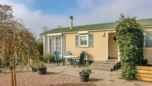 A cozy cottage with a tiled patio, two chairs, a table, and potted plants. - 2 bedroom nice home in Tzummarum (Tzummarum)