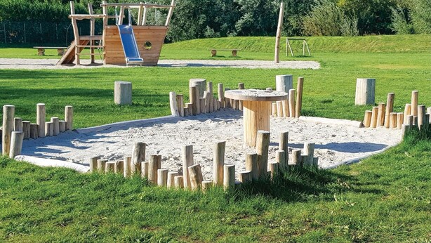 A playground with a slide, climbing structures, and a sandpit surrounded by wooden posts. - 2 bedroom nice home in Tzummarum (Tzummarum)