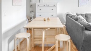 A small, bright room with a wooden table and two stools, a grey sofa, and a white dresser with drawers. - Stunning apartment in Vossestrand (Vossestrand)