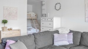 A modern, minimalist bedroom with a bunk bed, a dresser, and a gray sofa with decorative pillows. - Stunning apartment in Vossestrand (Vossestrand)
