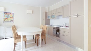 Cozinha moderna com mesa e cadeiras brancas, micro-ondas, fogão e armários.