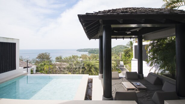 Ein Poolbereich mit Meerblick, einer überdachten Lounge und einem modernen Architekturstil.