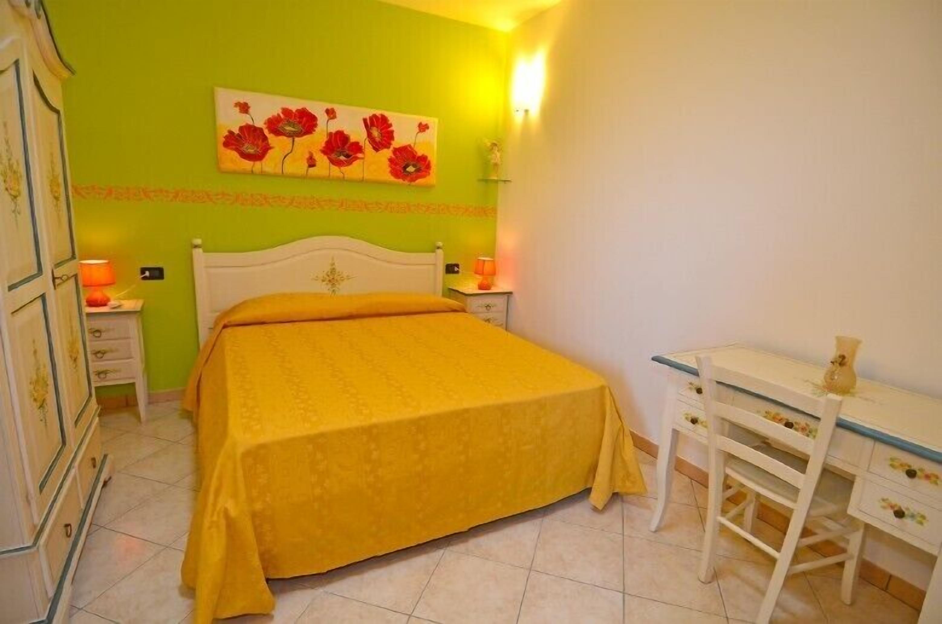 A bedroom with a bed, a desk, and a chair.