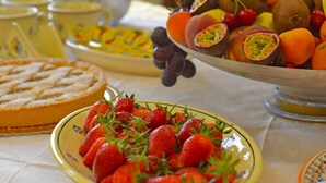 Una mesa con varias frutas, como fresas, uvas y kiwis, y un pastel.