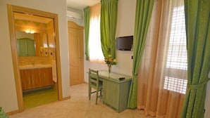 Habitación compacta con kitchenette, un escritorio y televisión.