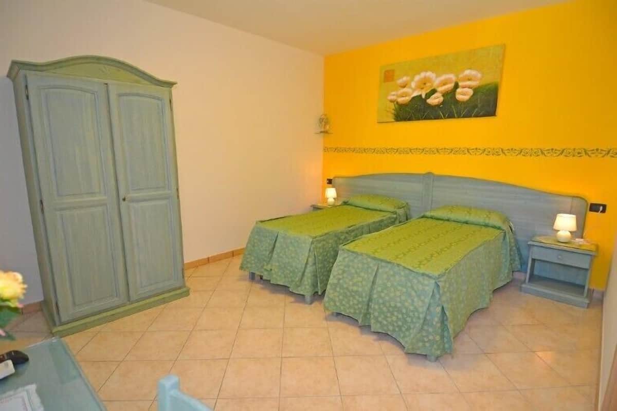 Een kamer met twee bedden, een kledingkast en een schilderij aan de muur.