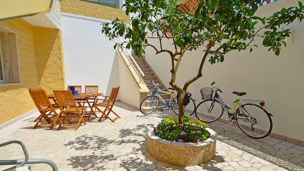 Un patio con una mesa, sillas, una jardinera y bicicletas.