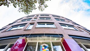 A multi-story building with a prominent logo at the ground level. - BoxHotel Hannover (Hannover)