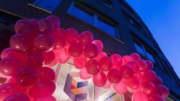 A building facade with a large number of pink balloons.