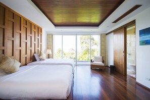 A hotel room with two beds, wooden paneling, a large window, and a view of trees.