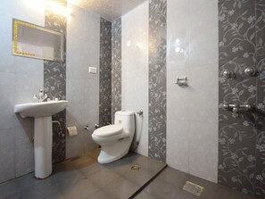 Un baño con lavamanos, inodoro y zona de ducha blancos.