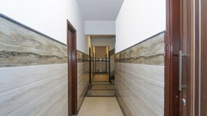 A corridor with marble walls and a wooden door on the right. - OYO Flagship 24448 Moon Light Guest House (Lucknow)