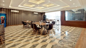 A modern hotel lobby with a checkered floor, a central dining area with tables and chairs, and a large window providing a view of the city. - Capital O 30351 S B Excellency (Jodhpur)