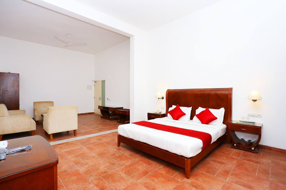 A hotel room with a large bed, two bedside tables, a desk, and a chair.