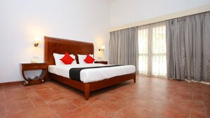 A bedroom with a wooden bed, two nightstands, a telephone, and a window with curtains. - Capital O 29855 Island Inn (Kanayannur)
