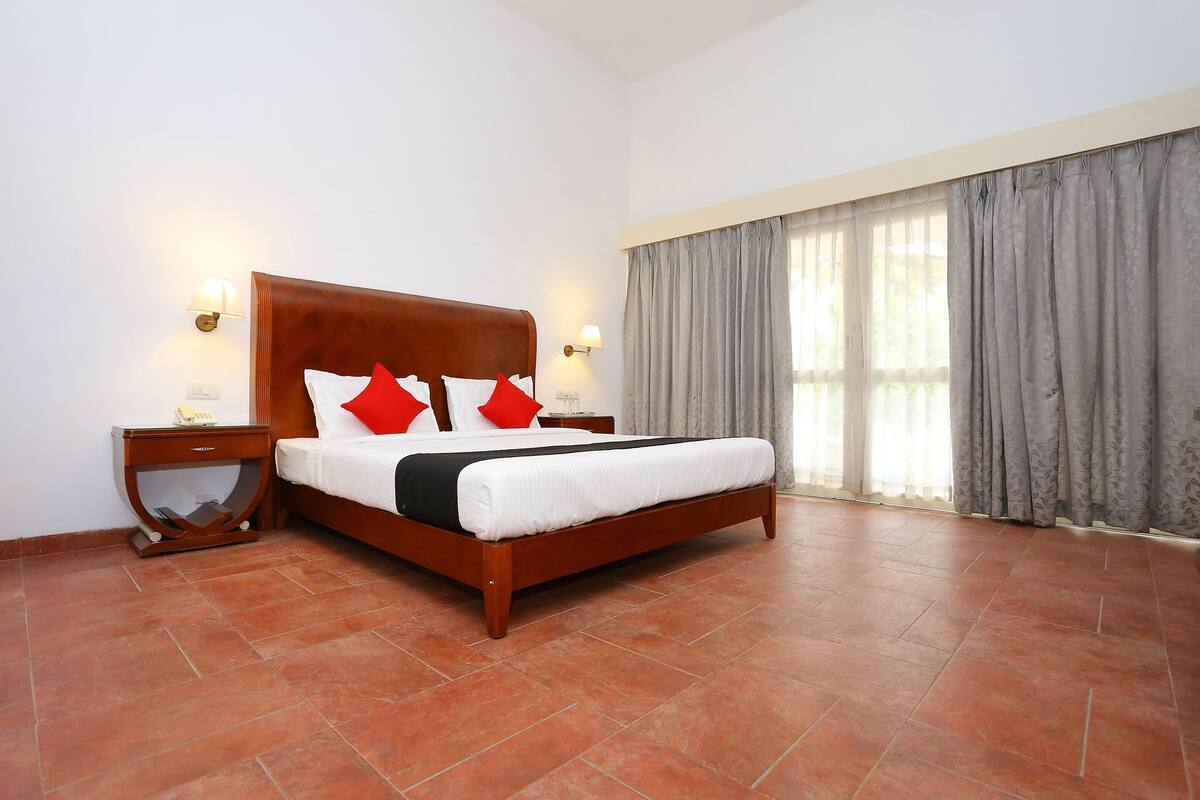 A bedroom with a wooden bed, two nightstands, a telephone, and a window with curtains.