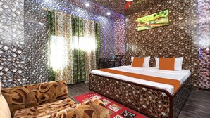 A bedroom with a bed, curtains, a ceiling fan, and a painting on the wall.