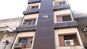 A multi-story building with a central vertical feature, multiple balconies, and air conditioning units.