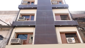 A multi-story building with balconies, air conditioning units, and a central vertical feature.