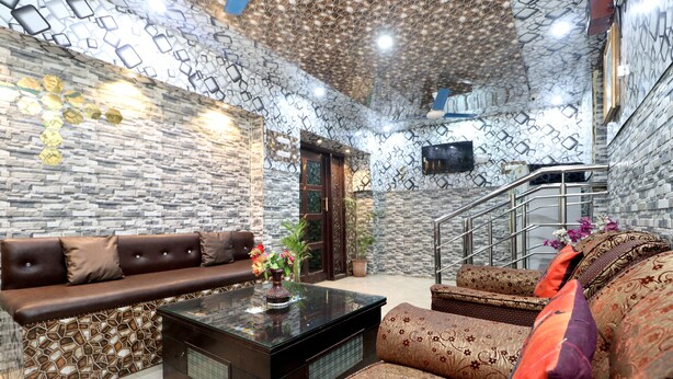 A modern living room with a stone-patterned wall, a brown leather sofa, a patterned sofa, and a glass coffee table.