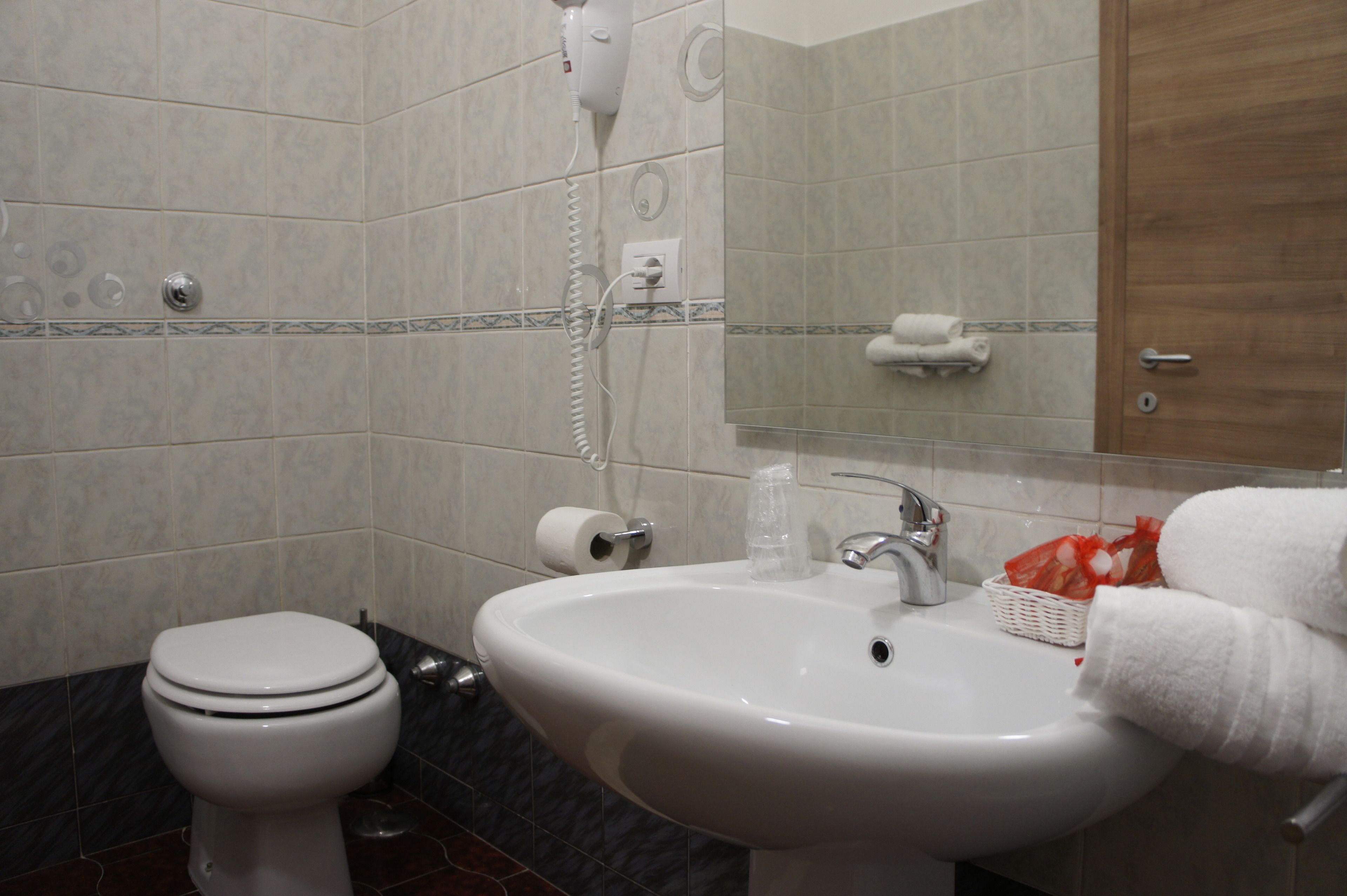 A bathroom with a toilet, sink, and a hairdryer on the wall.