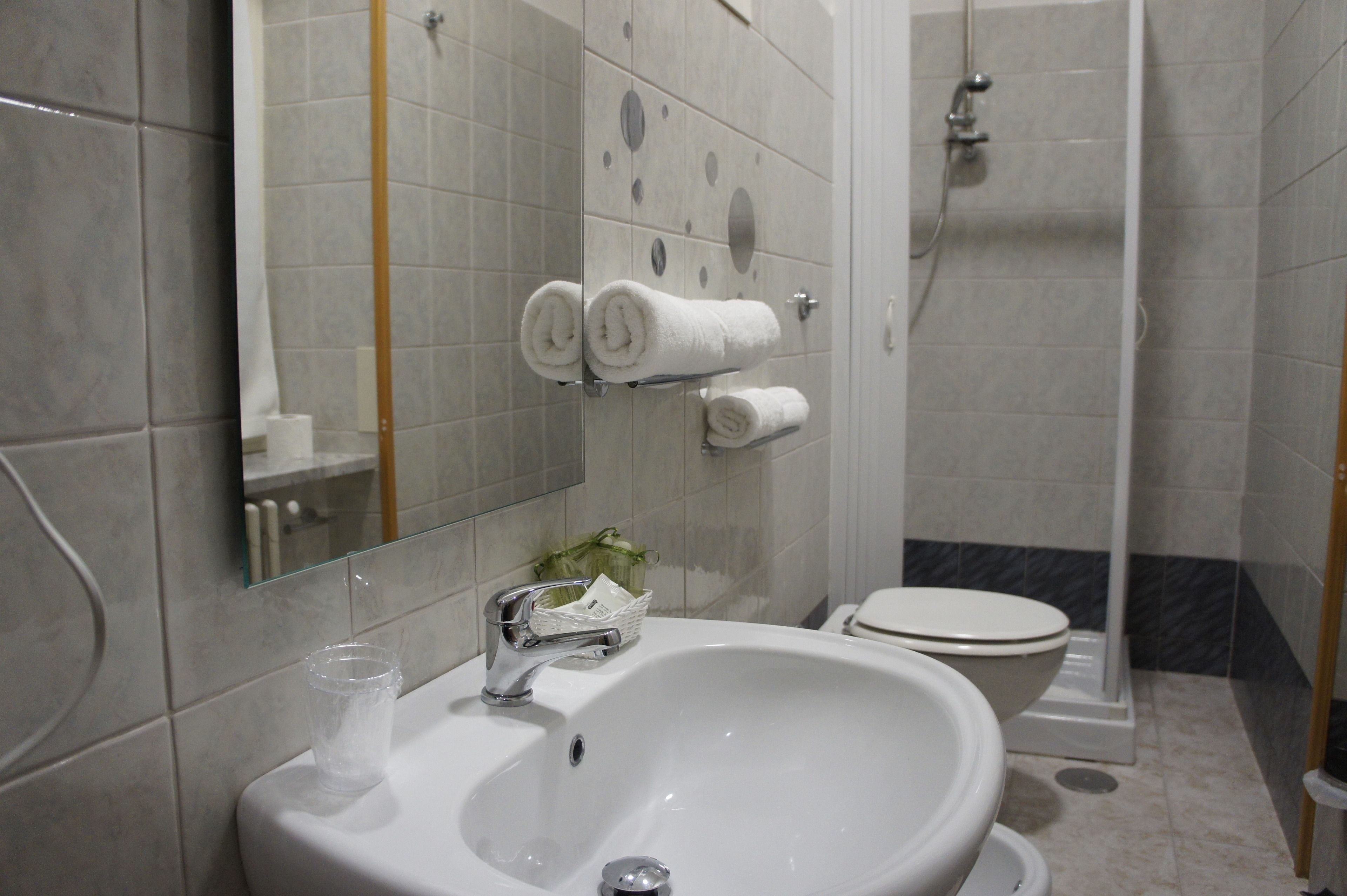A bathroom with a sink, mirror, toilet, and shower.