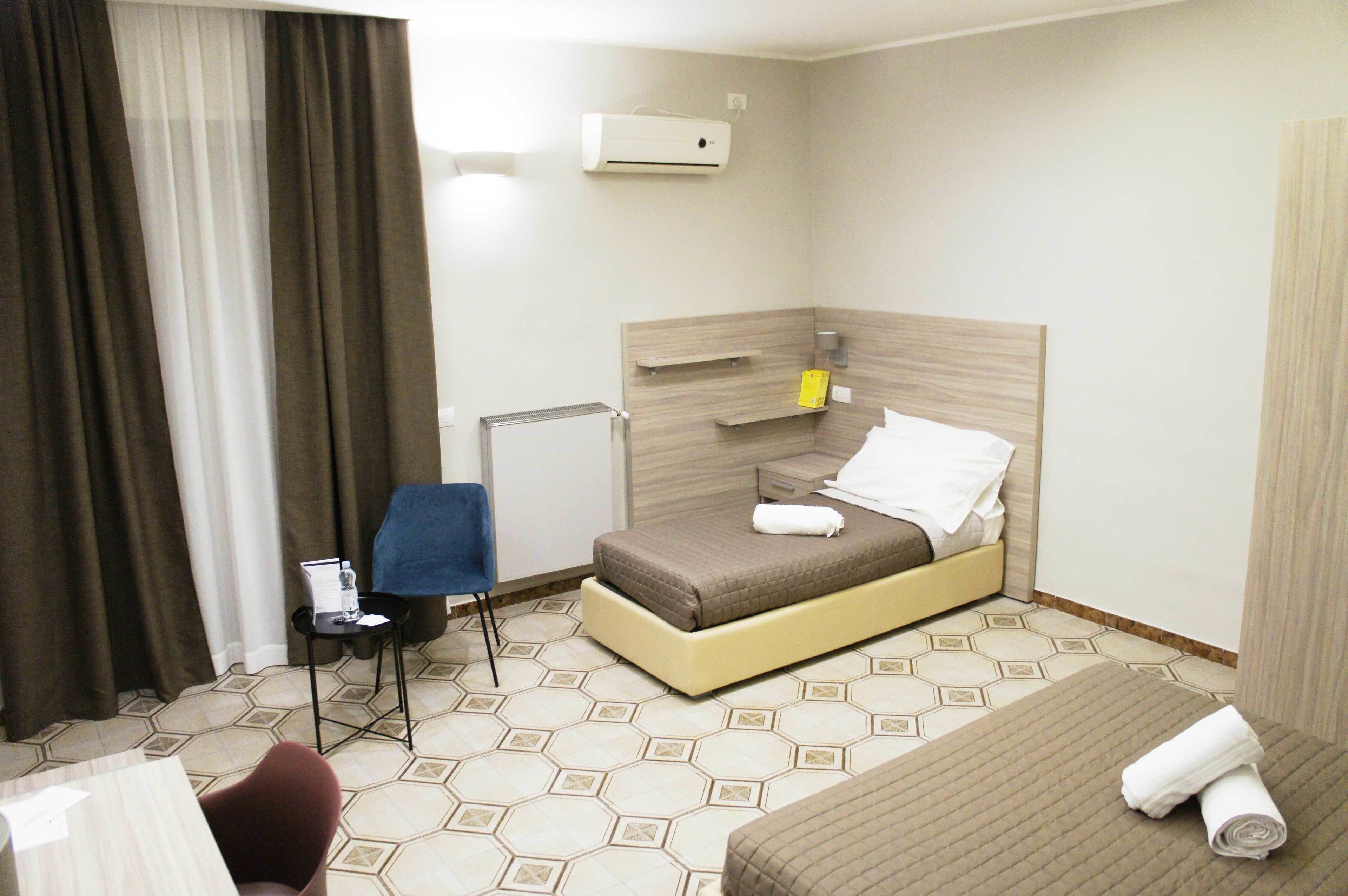 Una habitación de hotel con cama, una silla, una mesita y un escritorio.