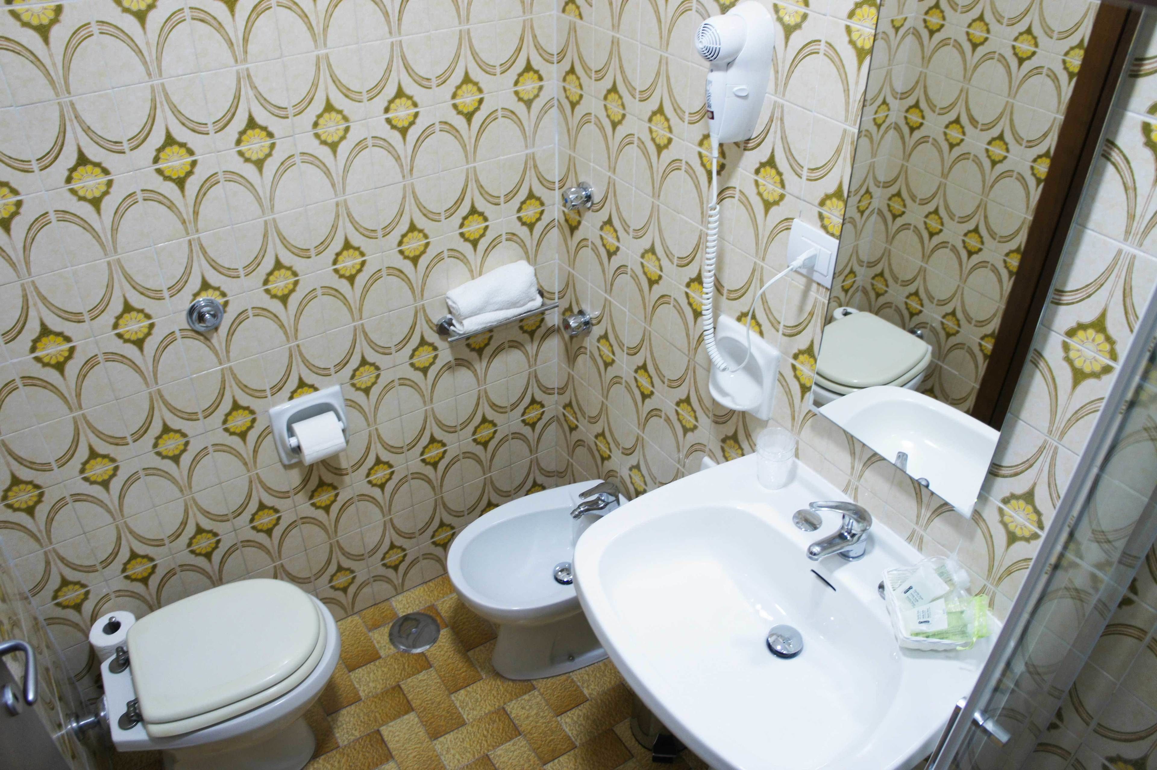 Une salle de bain avec deux toilettes, un lavabo, un miroir et un porte-serviettes.