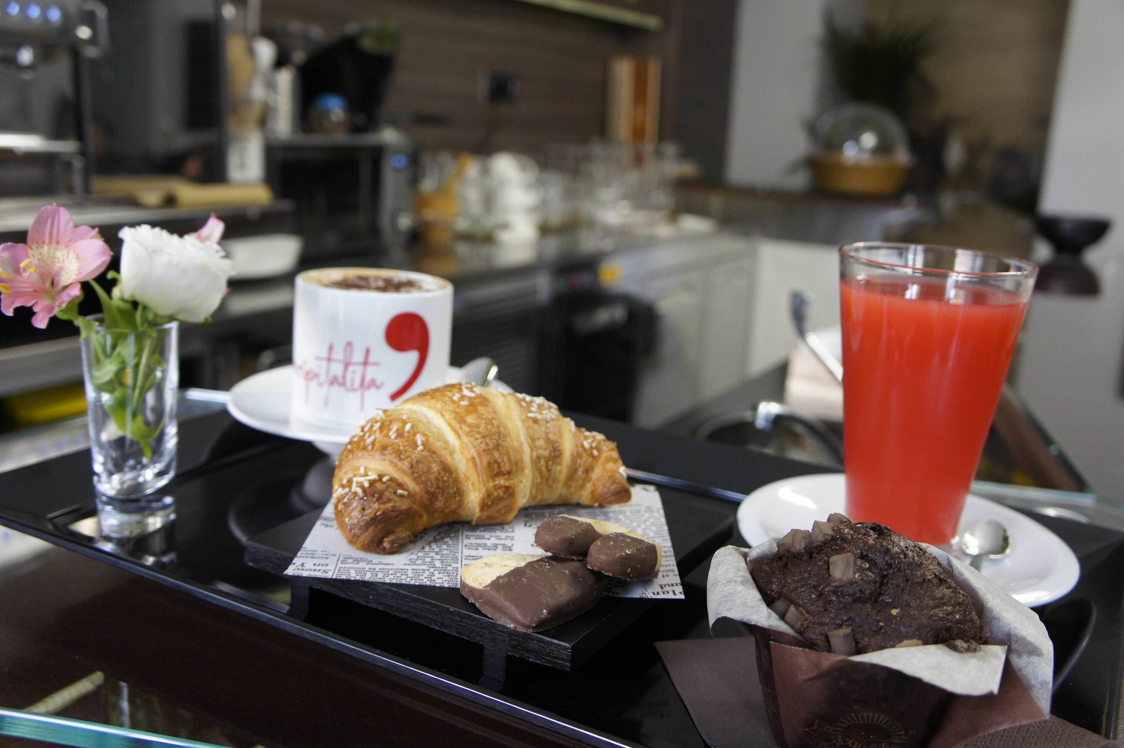 A breakfast tray with croissant, chocolate, and a glass of red juice.
