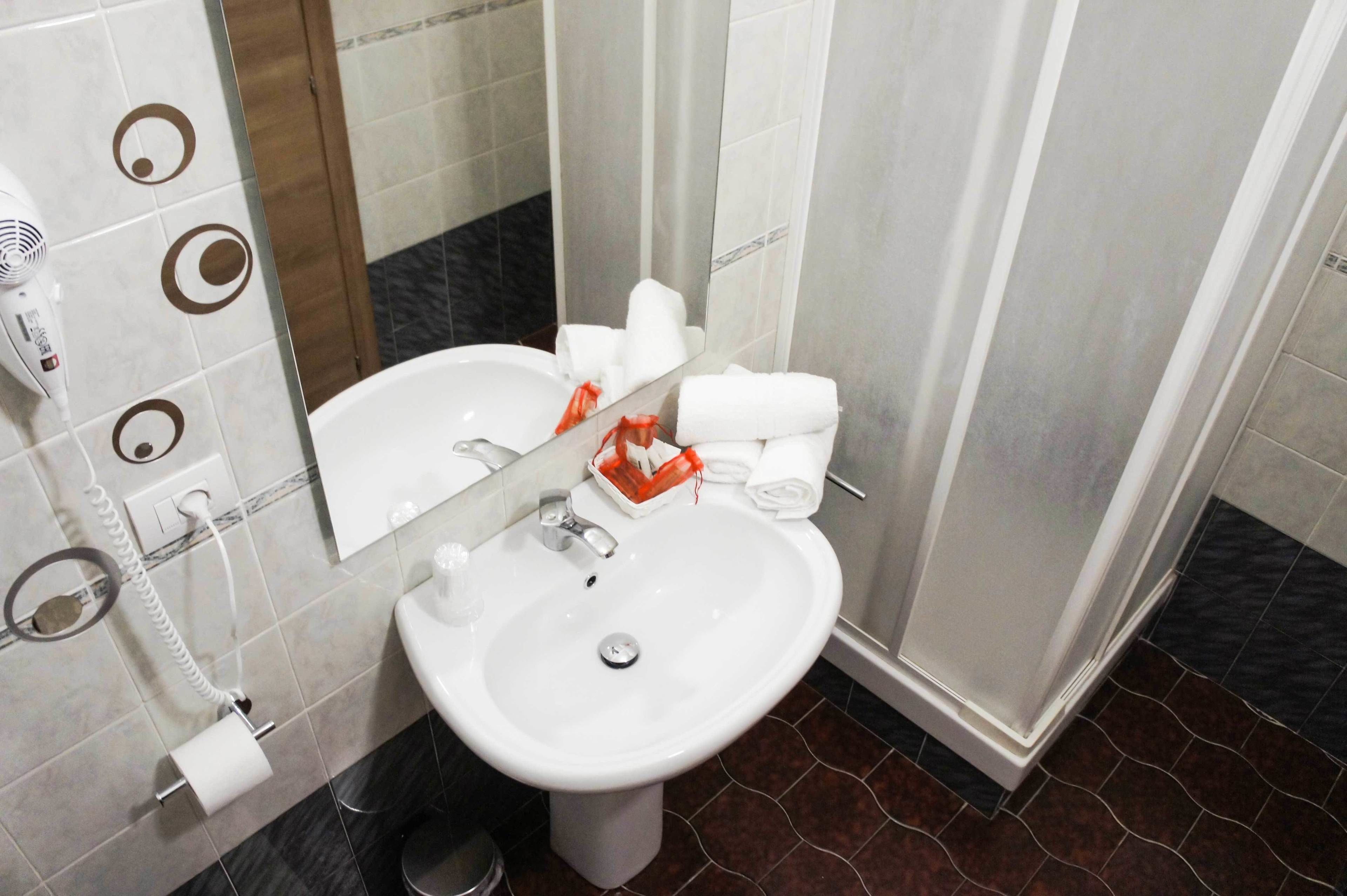 A bathroom with a white sink, a mirror, a hairdryer, and a towel rack.
