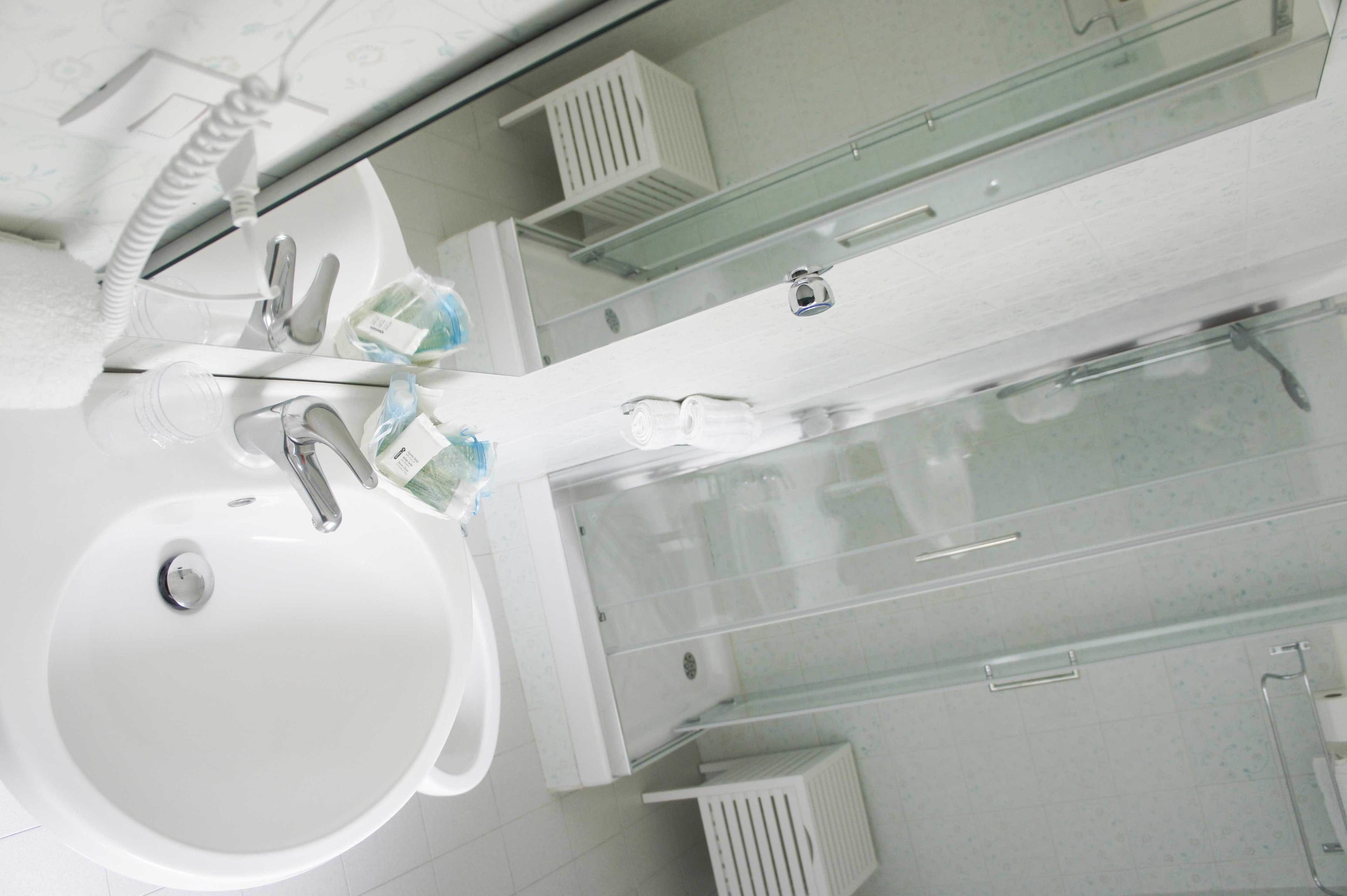 A modern bathroom with a white sink, a glass shower enclosure, and a mirror above the sink.
