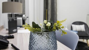A modern hotel room with a wooden desk, a lamp, a vase with white flowers, and a grey chair. - Albergo D'Onofrio (Telese)