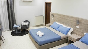 A hotel room with two beds, a chair, a small table, and a radiator. - Albergo D'Onofrio (Telese)