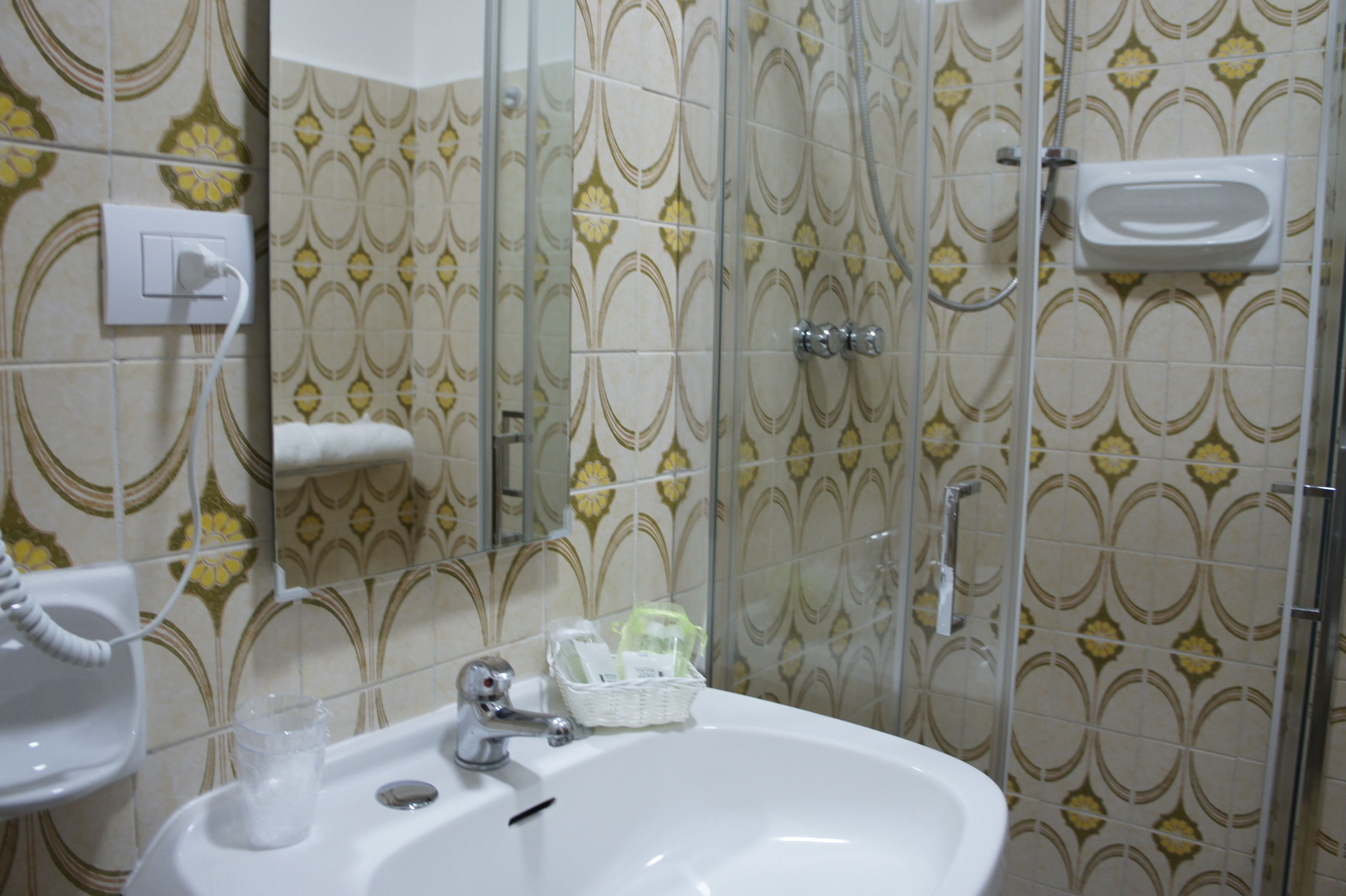 A bathroom with a sink, mirror, and shower.