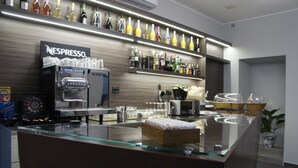 A bar area with a Nespresso coffee machine, a variety of liquor bottles, and a glass display counter. - Albergo D'Onofrio (Telese)