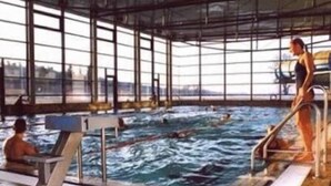 Una piscina interior con agua cristalina, un trampolín y una zona de espectadores.