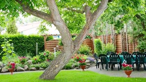 Un jardín con una pérgola de madera, mobiliario exterior y plantas en macetas.