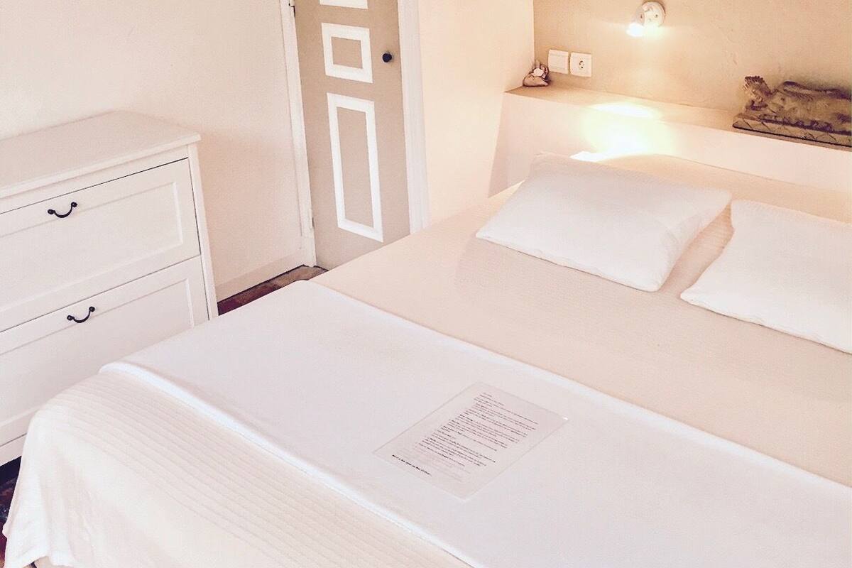 Un dormitorio ordenado con cama, mesitas de noche y una puerta.