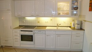 A kitchen with white cabinets, a dishwasher, an oven, a sink, and a coffee maker. - Wohnung Residenz am Wasser (Karlshagen)