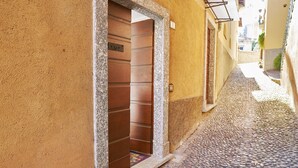 A narrow cobblestone street with a wooden door and a small step leading to a building. - Breathtaking view from a charming apartament (Menaggio)