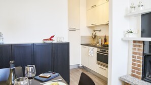 A modern kitchen with white cabinets, a brick fireplace, and a dining area with a table set for two. - Breathtaking view from a charming apartament (Menaggio)