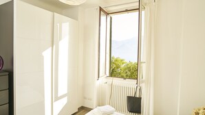 A bedroom with a large window, a radiator, and a neatly made bed with towels. - Breathtaking view from a charming apartament (Menaggio)