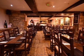 Un restaurante con paredes de piedra, mesas y sillas de madera y una zona de bar.