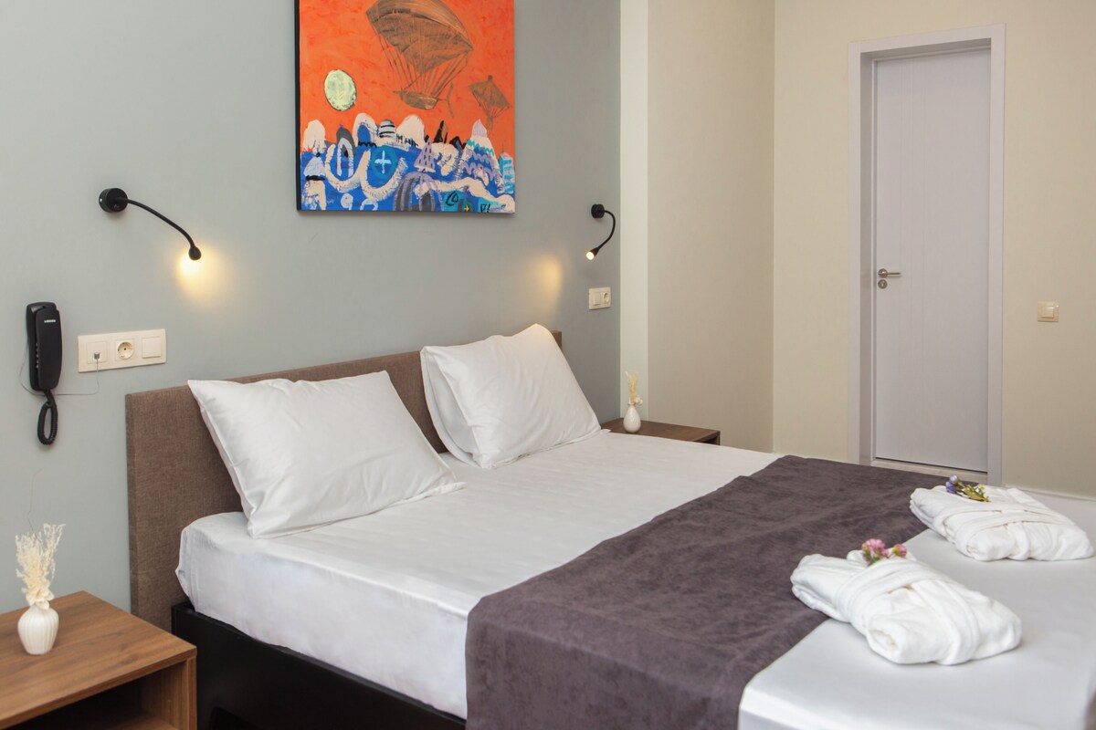 Ein Hotelzimmer mit einem Bett, einem Nachttisch, einem wandmontierten Telefon, einem Gemälde und einer Tür.
