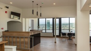 Un moderno hall de hotel con mostrador de recepción, zona de estar y amplios ventanales con vistas a la ciudad.