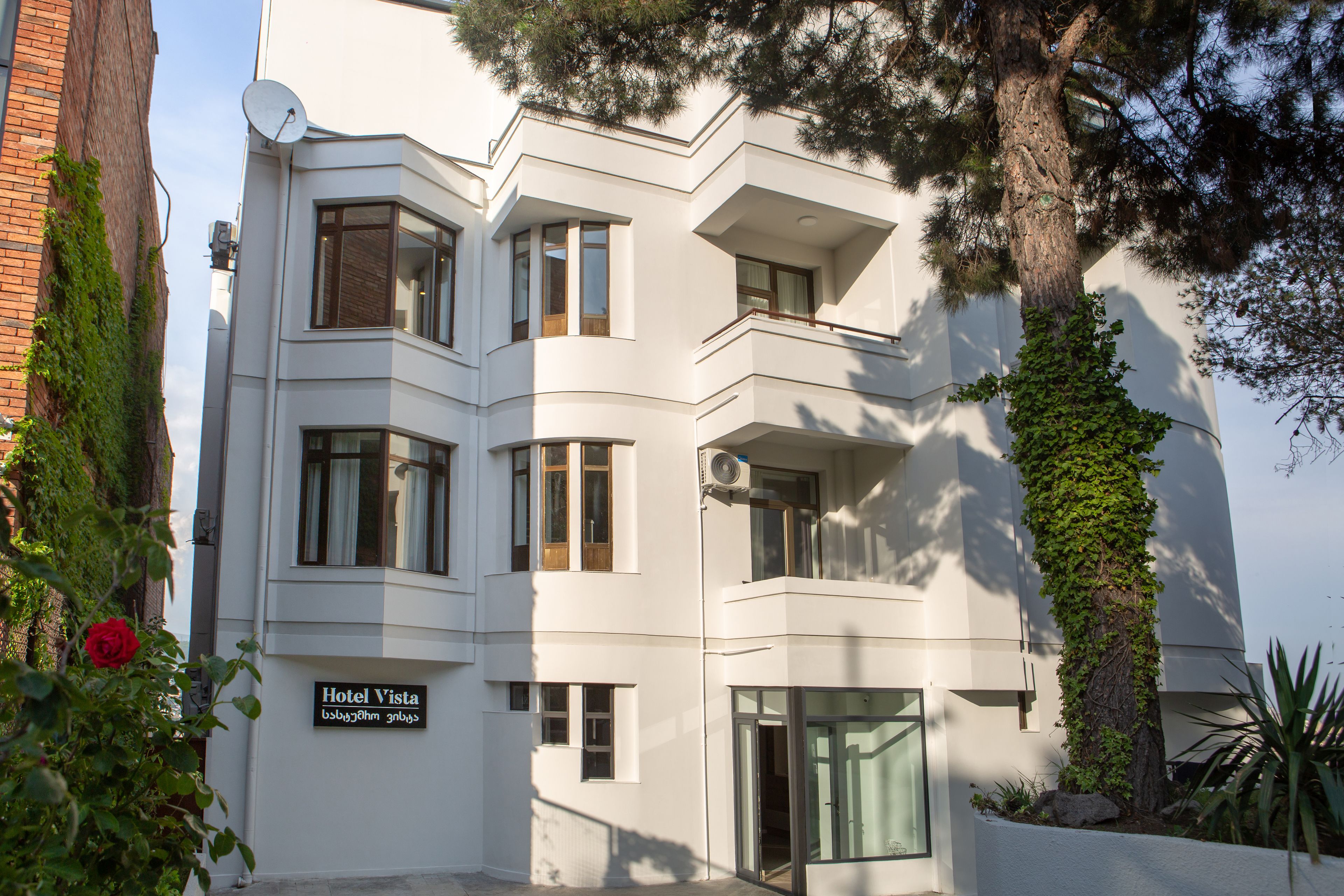 A modern hotel with a white facade, multiple windows, and a sign reading "Hotel Vista".