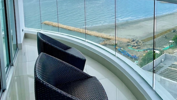 A balcony with a view of the sea and a distant shoreline. - Luxury Stay in Cartagena Prime Beachfront + Views (Cartagena)