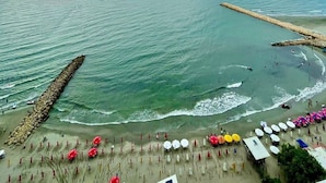 A beach with a long pier extending into the sea, a sandy shore with umbrellas and beach chairs, and a cloudy sky. - Luxury Stay in Cartagena Prime Beachfront + Views (Cartagena)
